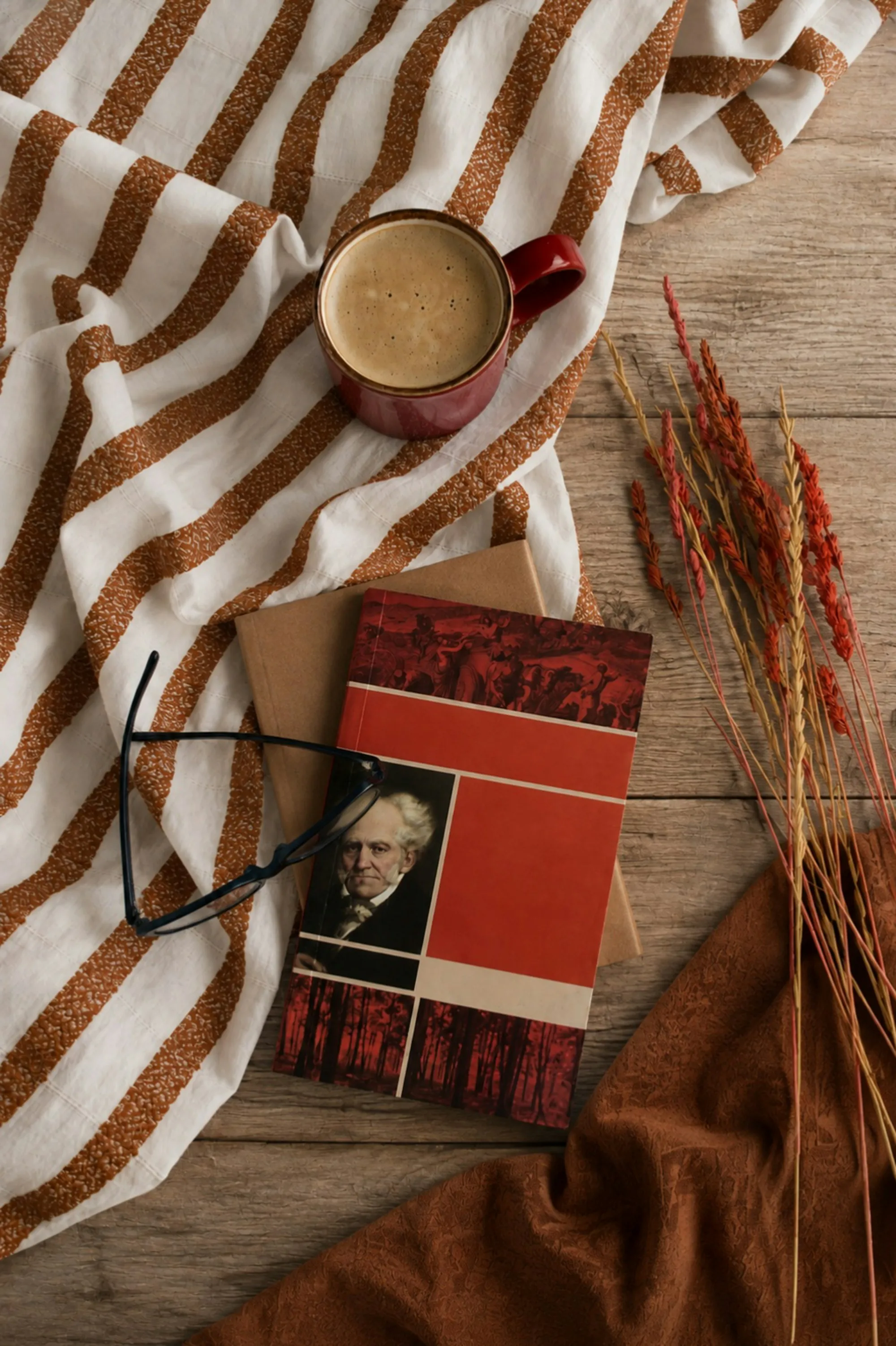 A mug, some books and a pair of reading glasses on a table