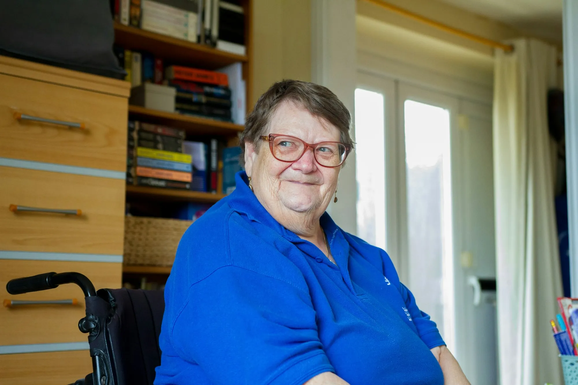 An older woman smiling in her chair at home
