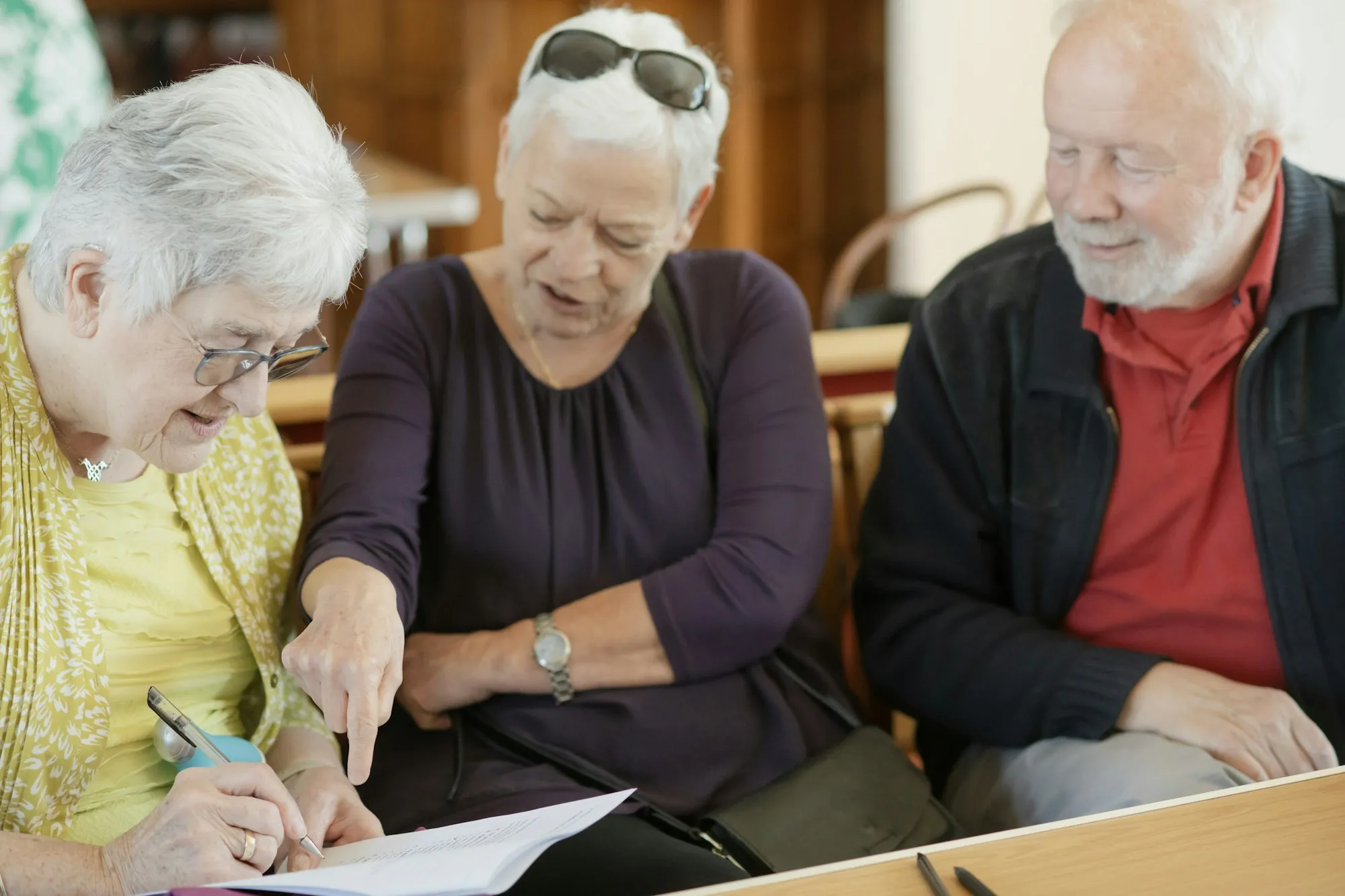 Three older adults reading a document together