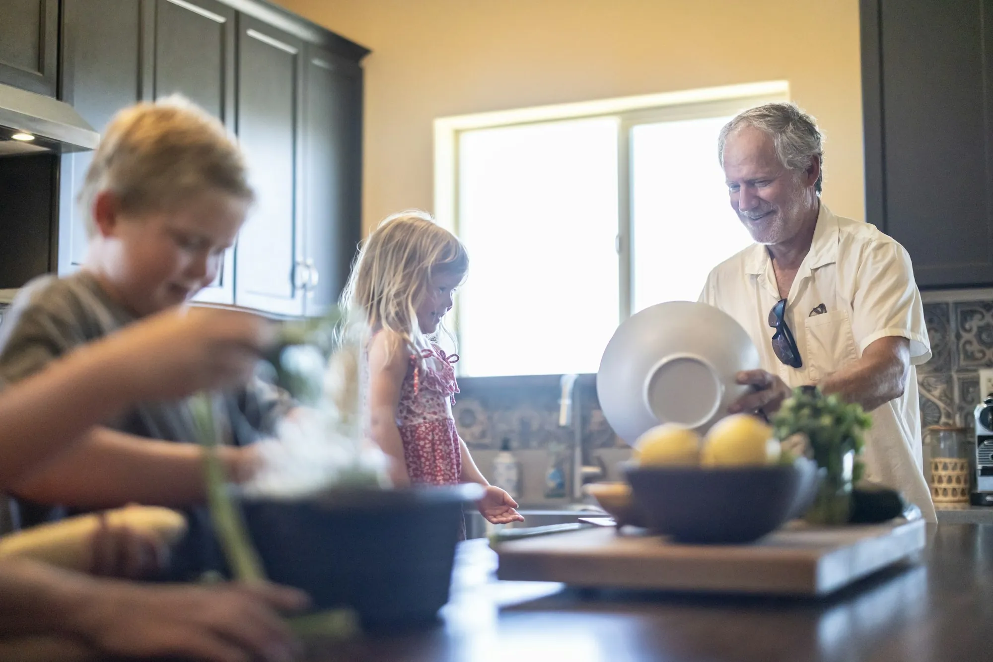 An older man and younger helpers preparing food in a kitchen