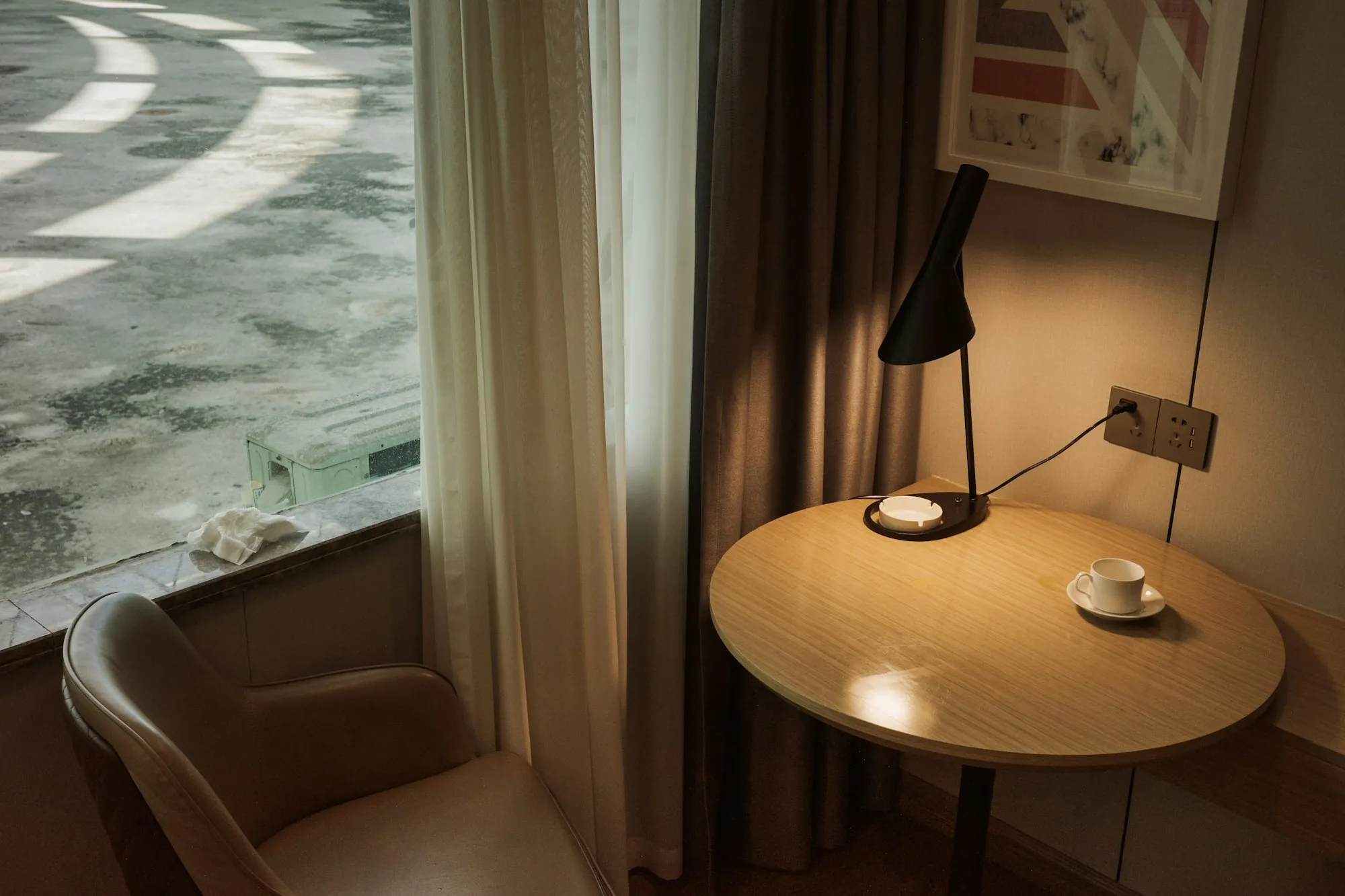 A round table and lamp beside a window